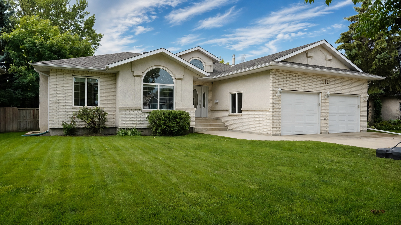 Front exterior with lawn and two-car garage